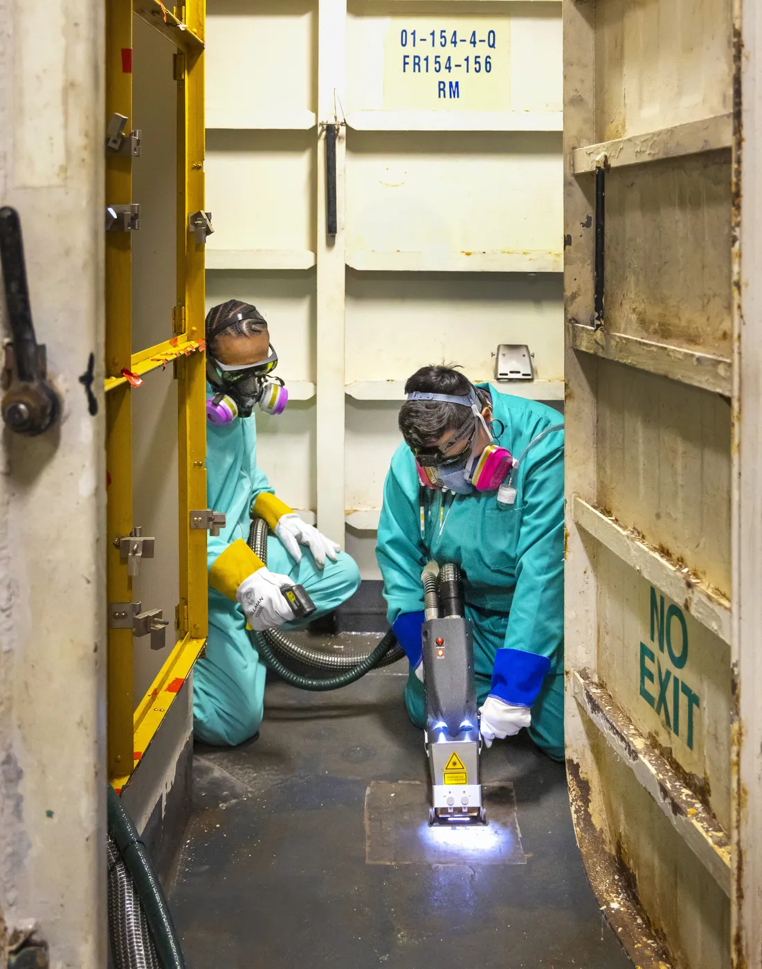Two operators removing coatings with laser ablation aboard USS Ronald Reagan