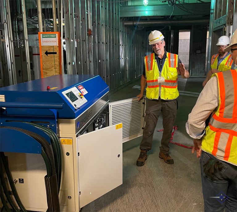 Laser professional talking in front of group with hard hats