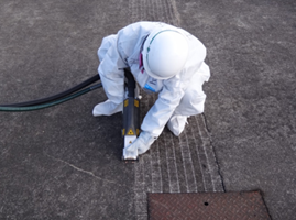 operator dressed in protective gear using a laser cleaning system on the ground in Fukushima, Japan after the 2011 earthquake