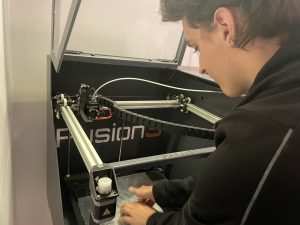Summer Intern pulls 3D printed part for laser optic from printer