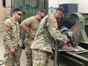 2 Soldiers Watch A third Use A Handheld Laser Cleaning System
