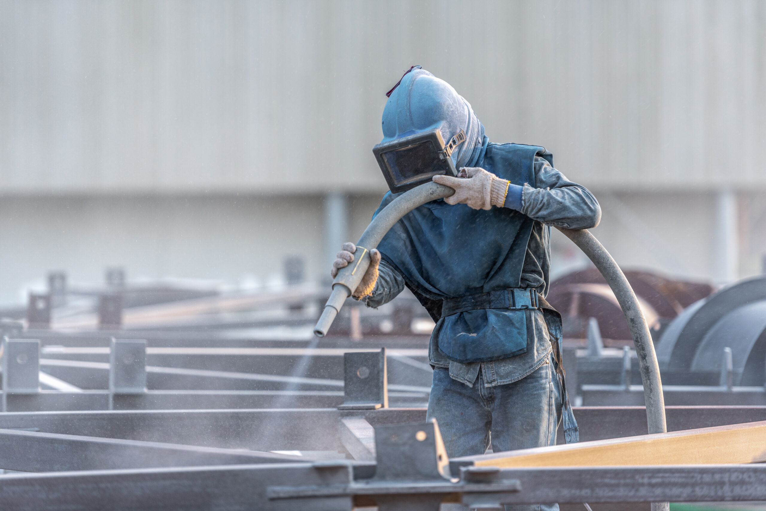 Sand blasting process, Industial worker using sand blasting process preparation cleaning surface on steel before painting in factory workshop